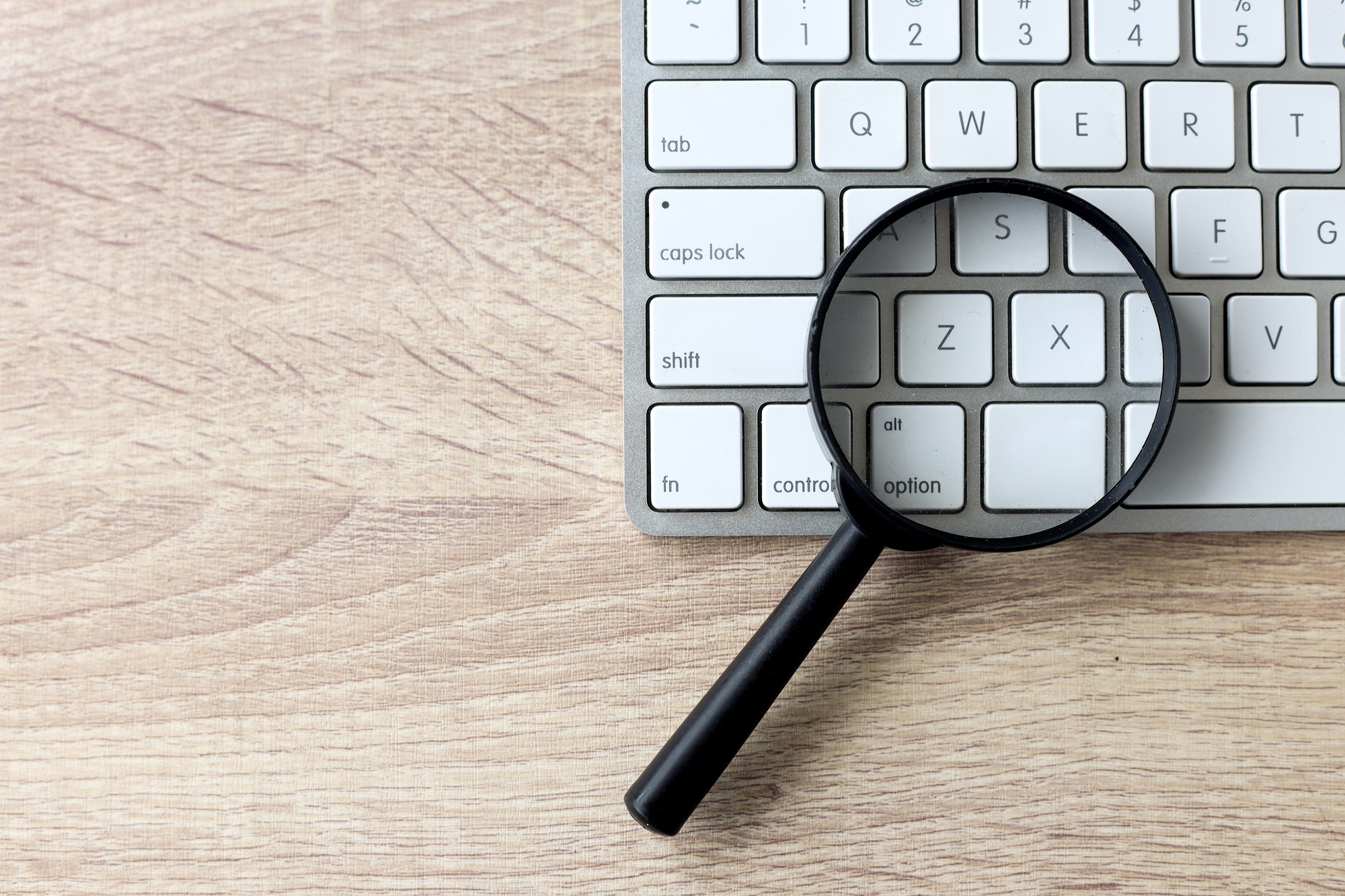 tronos Blog 5 Magnifying glass on a white keyboard. Web search and SEO concept
