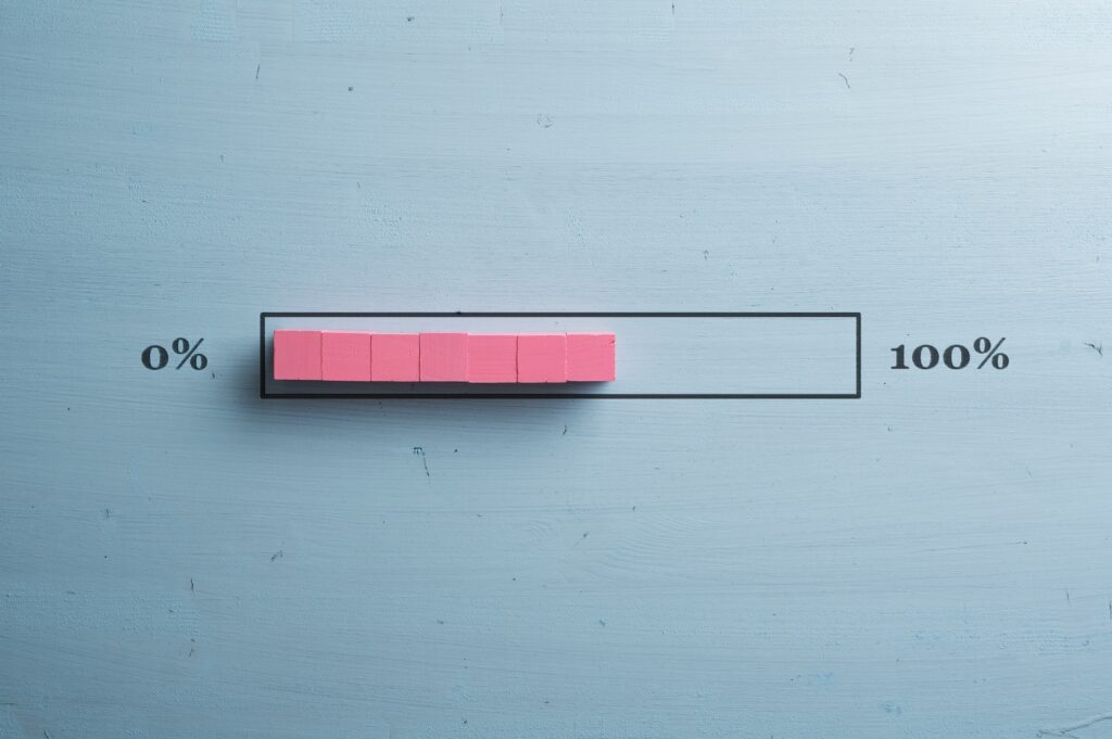 tronos Prečo má web pomalý loading a ako to opraviť? 5 Conceptual loading bar drawn over light blue wooden background with pink blocks showing progress